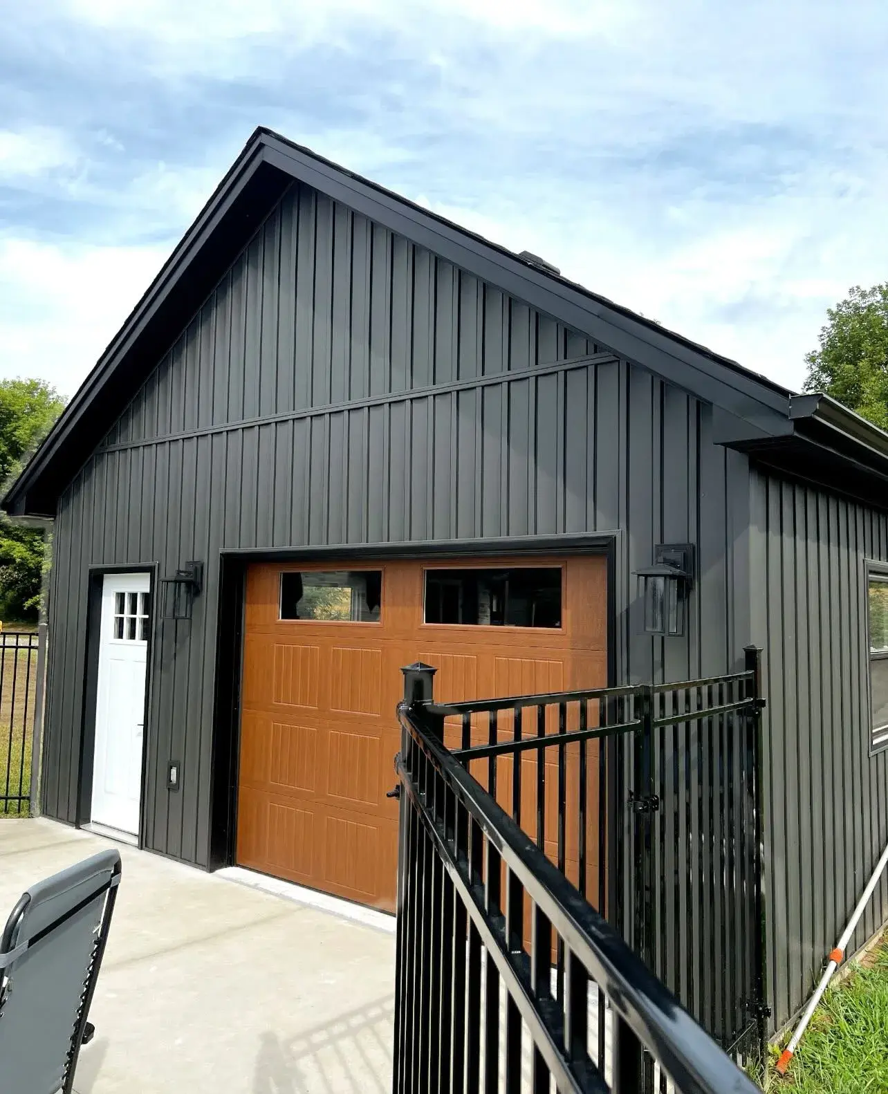 Dark exterior garage renovation with wood-tone overhead door